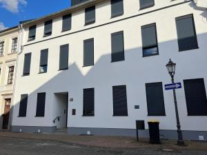 a white building with black shuttered windows and a street light at ZENITH STAY - hochwertige Apartments direkt in der Innenstadt in Erkelenz