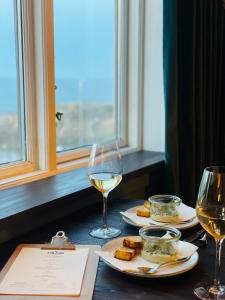 een tafel met twee glazen witte wijn en eten bij The Falcon Hotel in Allinge