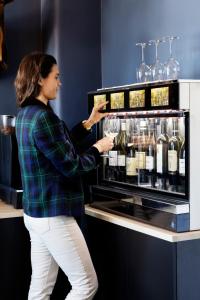 Una mujer está poniendo una copa de vino en una nevera. en The Falcon Hotel en Allinge