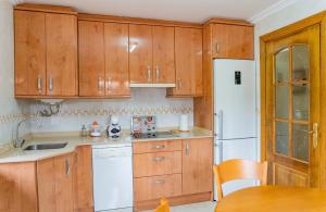 a kitchen with wooden cabinets and a white refrigerator at La Casita Verde de Cabárceno in Sobarzo