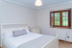um quarto branco com uma grande cama branca e uma janela em La Casita Verde de Cabárceno em Sobarzo
