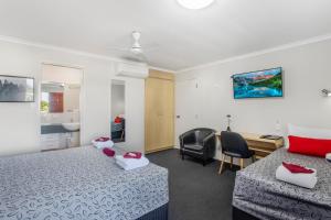 a hotel room with two beds and a desk at Citywalk Motor Inn in Rockhampton