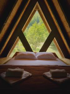 Bett in einem Zimmer mit einem großen Fenster in der Unterkunft Woodland Brezna in Plužine