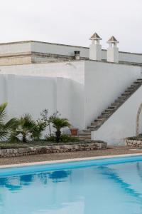 a swimming pool in front of a white building at Masseria Gorgognolo in Ostuni