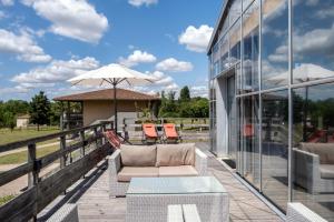 - une terrasse avec un canapé et un parasol dans un bâtiment dans l'établissement Résidence Pierre & Vacances Les Rives de la Seugne, à Jonzac