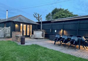 a group of chairs sitting on a deck next to a building at Stable Cottage at Lee Wick Farm Cottages & Glamping in Clacton-on-Sea