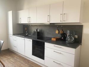 a kitchen with white cabinets and a black stove top oven at BIELEFELD CITY APARTMENTS - Loft - 2 Schlafzimmer, voll ausgestattete Küche, modernes Badezimmer, schnelles WLAN in Bielefeld