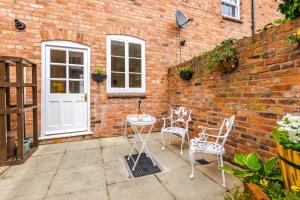 un patio con 2 sillas, una mesa y una pared de ladrillo en Albion Cottage, en Chester