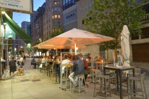 eine Gruppe von Menschen sitzt an Tischen mit einem Regenschirm in der Unterkunft El apartamento de San Javier by Just Room in Santander + 26 Fotos