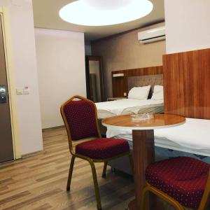 メルスィンにあるGrand Mardin Hotelのテーブルとベッド2台が備わるホテルルームです。