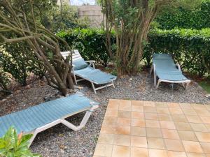 tres bancos azules sentados en un patio con árboles en Maison familiale dans une rue paisible, en Gouville-sur-Mer