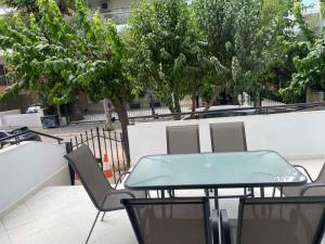 Comfortable Apartment Near to Metro & Hospitals في أثينا: طاولة خضراء وكراسي على فناء به اشجار