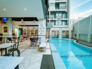 a swimming pool with tables and chairs on a building at Ratri Hotel Phuket Old Town in Phuket