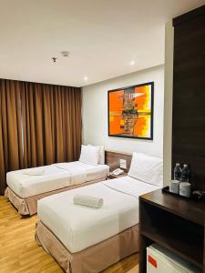um quarto de hotel com duas camas e uma secretária em Frenz Hotel Kuala Lumpur em Kuala Lumpur