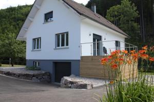 a white house with a balcony and some flowers at A l Orée du Bois in Rimbach-près-Masevaux