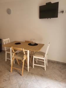 mesa de madera con sillas y TV en la pared en Monolocale ai cavallucci, en Terracina
