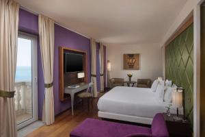 a hotel room with a bed and a large window at NH Collection Taormina in Taormina