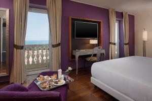 Una habitación de hotel con una cama y una mesa con una bandeja de comida en NH Collection Taormina, en Taormina