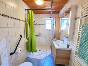 a bathroom with a green shower curtain and a sink at Huus de Freese 35224 in Beningafehn