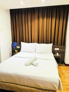 a large white bed with a towel on it at Frenz Hotel Kuala Lumpur in Kuala Lumpur