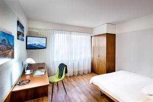 a hotel room with a bed and a desk and a bed and a desk at City Hotel Biel Bienne Free Parking in Biel