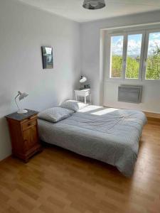 ein Schlafzimmer mit einem Bett und einer Lampe auf einem Holzboden in der Unterkunft 4* Vue sur la colline de Vézelay in Saint-Père