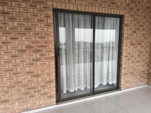 a window with white curtains on a brick wall at Lotus Accommodation in Kingsburgh