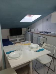 eine Küche mit einem weißen Tisch mit Tellern und Stühlen in der Unterkunft casetta al mare in Sapri
