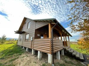 a large wooden cabin in a grassy field at AVALON - Котедж на озері in Boryslav