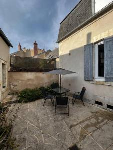 a patio with a table and chairs and an umbrella at Appartement T2 avec terrasse proche cathédrale in Bourges