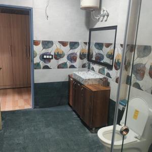 La salle de bains est pourvue de toilettes, d'un lavabo et d'un miroir. dans l'établissement Hotel Pearl Residency, à Mukteswar