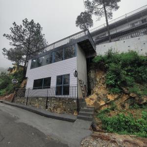 a white building on a hill with stairs in front at Hotel Pearl Residency in Mukteshwar