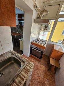 uma cozinha com um lavatório e um fogão forno superior em Apartament Rebeca Central em Târgu Jiu