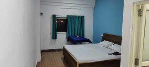 a bedroom with a bed and a window with green curtains at OYO Sailors Galley in Gwalior
