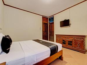 a bedroom with a bed and a tv on a wall at Capital O 92894 Griya Lathifah Homestay Syariah in Kalasan