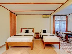 a bedroom with two beds and a table at Capital O 92894 Griya Lathifah Homestay Syariah in Kalasan