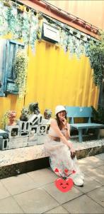 a woman in a dress sitting on a bench at H-HOMESTAY CONTAINER LAGI BEACH in Lagi