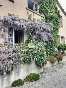 a building with wisteria on the side of it at Les chambres du roc St Jean in Gluiras