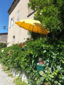 a yellow umbrella and some plants and a building at Les chambres du roc St Jean in Gluiras