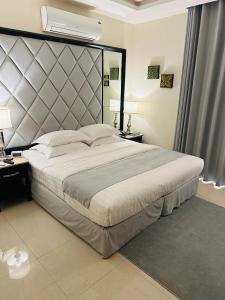 ein Schlafzimmer mit einem großen Bett mit einem großen Kopfteil in der Unterkunft كرم النخلة للشقق المخدومة in Riad