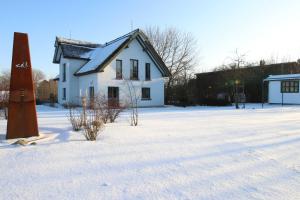 Ein weißes Haus im Schnee neben einer Straße in der Unterkunft Reetdachhaus im Fischerdorf in Freest