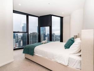 a bedroom with a large bed and large windows at Homely Urban Oasis in Melbourne