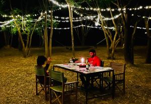 Ein Mann und ein Kind sitzen an einem Tisch mit Lichtern in der Unterkunft Funky Leopard Safari Lodge Bordering Yala National Park in Kataragama