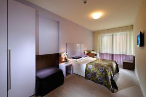 a hotel room with a bed and a chair at Hotel Luciana in Bibione