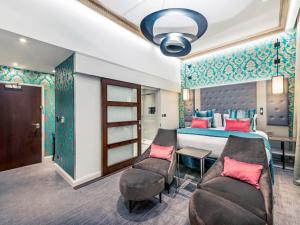 una camera con letto, divano e tavolo di Mercure London Hyde Park Hotel a Londra