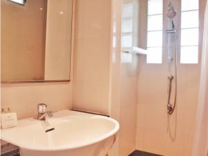een badkamer met een witte wastafel en een douche bij The Finn Hotel / เดอะฟินน์โฮเทล in Ban Liap