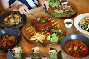 une table recouverte de plaques alimentaires avec de la viande et des frites dans l'établissement The Finn Hotel / เดอะฟินน์โฮเทล, à Ban Liap