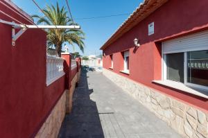 Puerto de GandíaにあるCerezoのヤシの木のある赤い建物2棟の間の路地