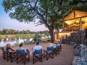 a group of people sitting in chairs by a river at Bundox River Lodge in Hoedspruit