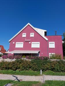a red building with flowers in front of it at Pension am Kirchberg in Wehringen
